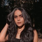 A beautiful woman posing in natural sunlight with lush hair, captured outdoors in Rio de Janeiro.